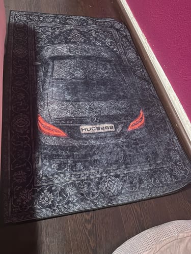Dark sports car rug displayed beside a wall