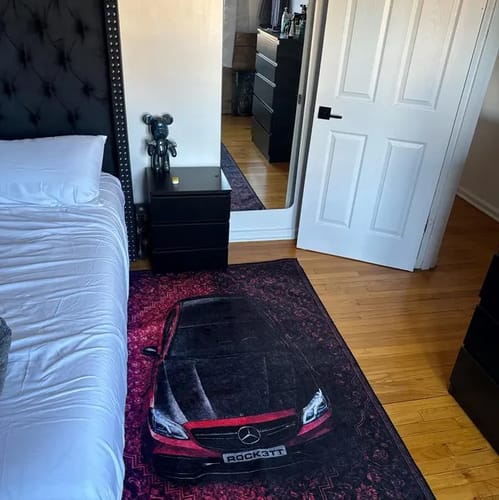 Red and black car rug displayed beside a bed