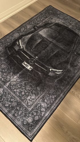 Black BMW car rug displayed on a wooden floor